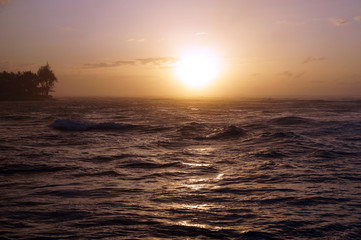Sunset over the ocean with waves moving to shore
