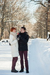 Fototapeta na wymiar Happy couple hug with lollipops in winter park