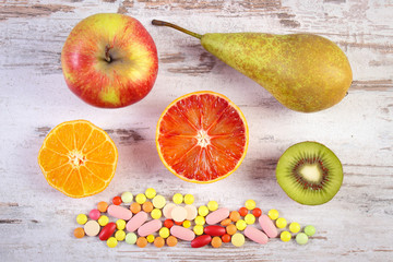 Fresh fruits and colorful medical pills, choice between healthy nutrition and medical supplements