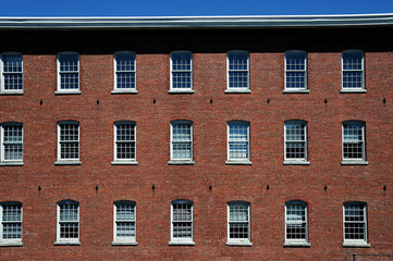 old red brick factory building exterior with many small windows, facade view