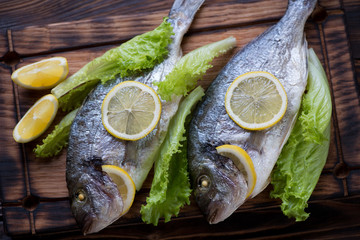 Close-up of two baked dorados with lemon and green salad