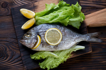 Above view of baked dorado fish with lemon and fresh green salad