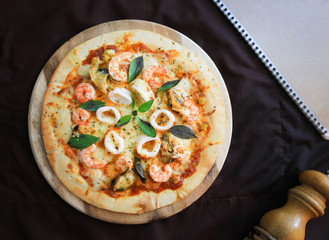 Delicious pizza with seafood on wooden stand, top view