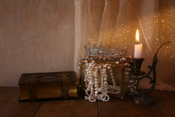 queen crown, white pearls next to old book
