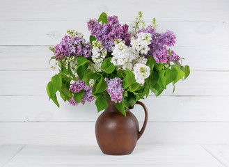 Lilac Bouquet in clay jug on background of shabby wooden planks
