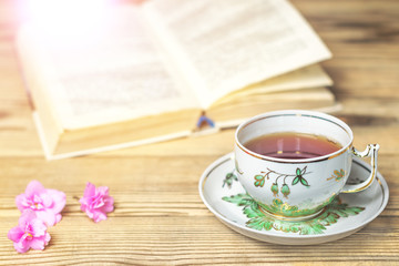 Tea cup, the book and flowers on the wooden table