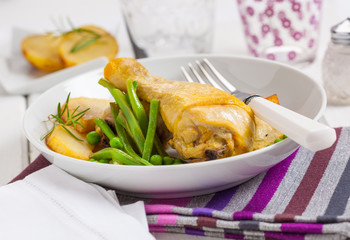Fried chicken leg with green beans, peas and potatoes.