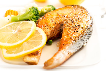 Grilled salmon and vegetables on white plate macro