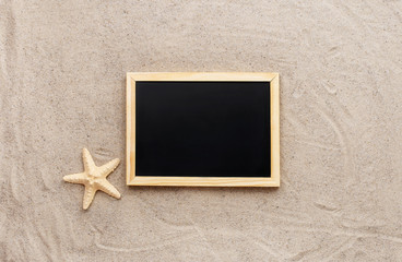 Blank small blackboard on beach sand with starfish