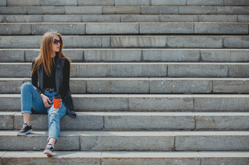 Young girl sitting on the steps with coffee in glasses.