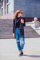 Beautiful girl standing on the street with coffee.