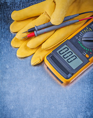 Digital electric tester safety gloves on metallic background