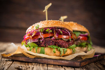 Tasty vegetarian beet burgers on wooden table. - obrazy, fototapety, plakaty