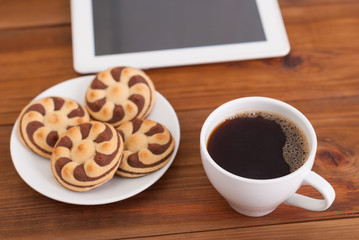 Cup of coffee and cookies a digital tablet on the table.