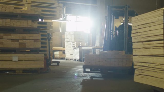 Forklift operator is driving in lumber factory warehouse. Shot on RED Cinema Camera.