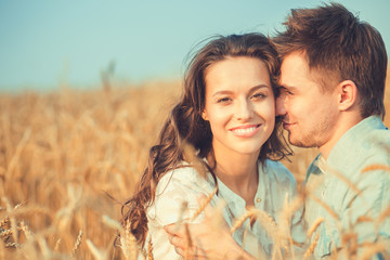 Young couple in love outdoor.Stunning sensual outdoor portrait of young stylish fashion couple posing in summer in field.Happy Smiling Couple in love.They are smiling and looking at each other