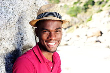 Handsome young man with hat smiling at the beach