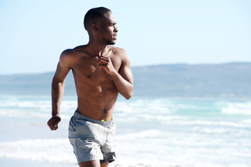 Muscular young man running along the beach