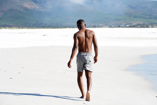 Young man walking barefoot on beach