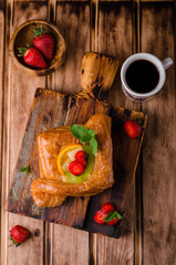 Freshly baked puff pastry with fruits and strawberries on wooden background. Selective focus. Top view