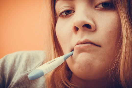 Sick ill woman with digital thermometer in mouth.