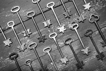 Fototapeta premium Some door keys aligned on old wooden surface, safety and security concept background