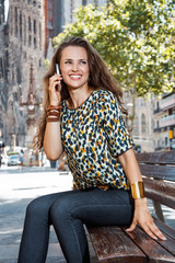 Smiling woman sitting on a bench and talking smartphone