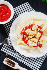 
Italian cuisine , pasta , spaghetti with cheese , tomato sauce , fried chicken and spices on a wooden background