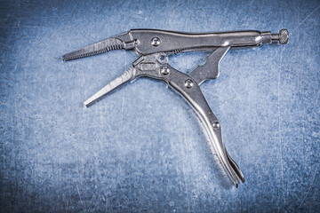 Stainless locking pliers with open jaws on metallic background