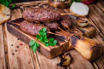 Roasted kebab skewer with spices on cutting board and wooden background. Selective focus