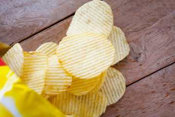 Opened pack with potato chips over wooden table