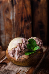 Chocolate ice cream with condenced milk on vintage wooden background. Selective focus