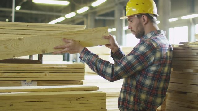 Lumber mill worker makes quality control of the wood in a warehouse. Shot on RED Cinema Camera.
