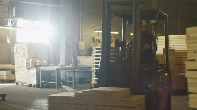 Forklift operator is driving in lumber factory warehouse. Shot on RED Cinema Camera.