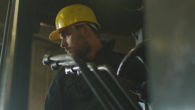 Forklift operator is driving in lumber factory warehouse. Shot on RED Cinema Camera.