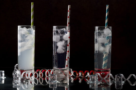 Set from three a collins glass with cocktails and colored straws.