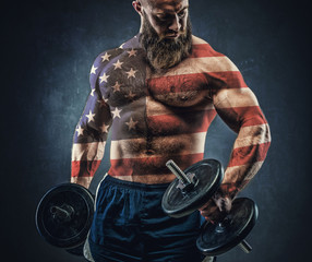 Power athletic bearded man in training pumping up muscles with d