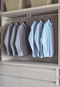 Light blue and grey shirts in light wooden wardrobe