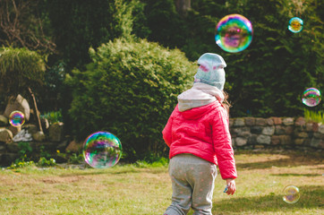 dziecko bawi się bańkami mydlanymi w ogrodzie   © Filip Olejowski