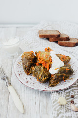 
National traditional Ukrainian and Russian cuisine , a dish called cabbage rolls , stewed rice with minced meat in cabbage leaves with sour cream , carrots and spices on a wooden background