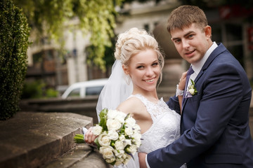Wedding couple with bouquet outdoors. having fun  embrace.  emotional portrait. happy married. wedding day