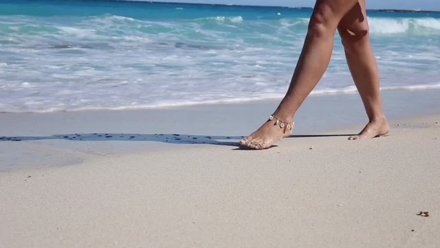 Beautiful woman legs, walking along the beach. Leaving footprints on sand
