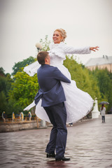 Wedding couple on alley next to city lake. Groom and bride together  dancing. Happy Married Young...