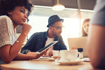 Fototapeta premium Young friends at a coffee shop with laptop and digital tablet