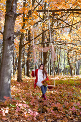 an expectant mother goes for a walk in the autumn park of swing