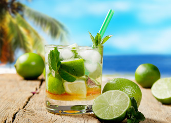 Mojito lime drink on wood with blur beach background