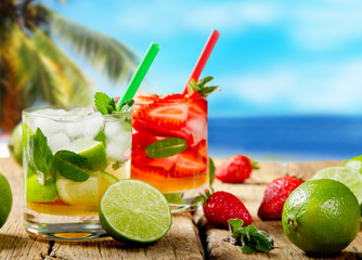 Mojito lime and strawberry drinks on wood with blur beach background