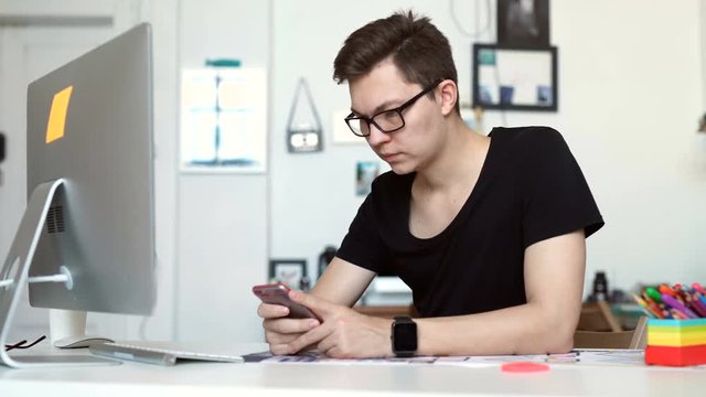 oung man working from home using smart phone and notebook computer