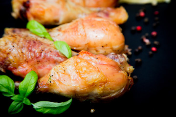 Roasted chicken legs with basil on the black background