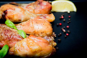 Roasted chicken legs with basil on the black background